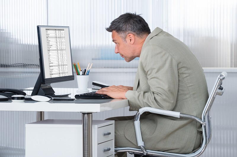 man rounded forward and working at computer