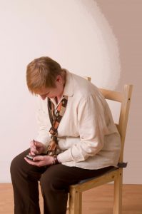 woman seated bent over texting