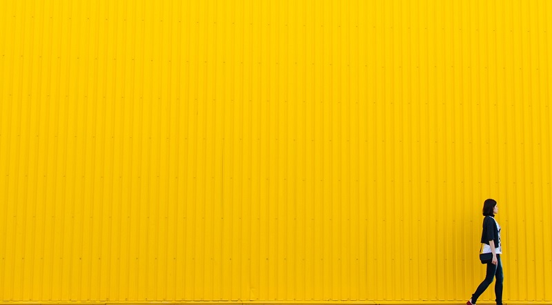 woman walking against a yellow background