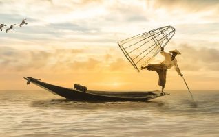 man balancing on edge of his fishing boat